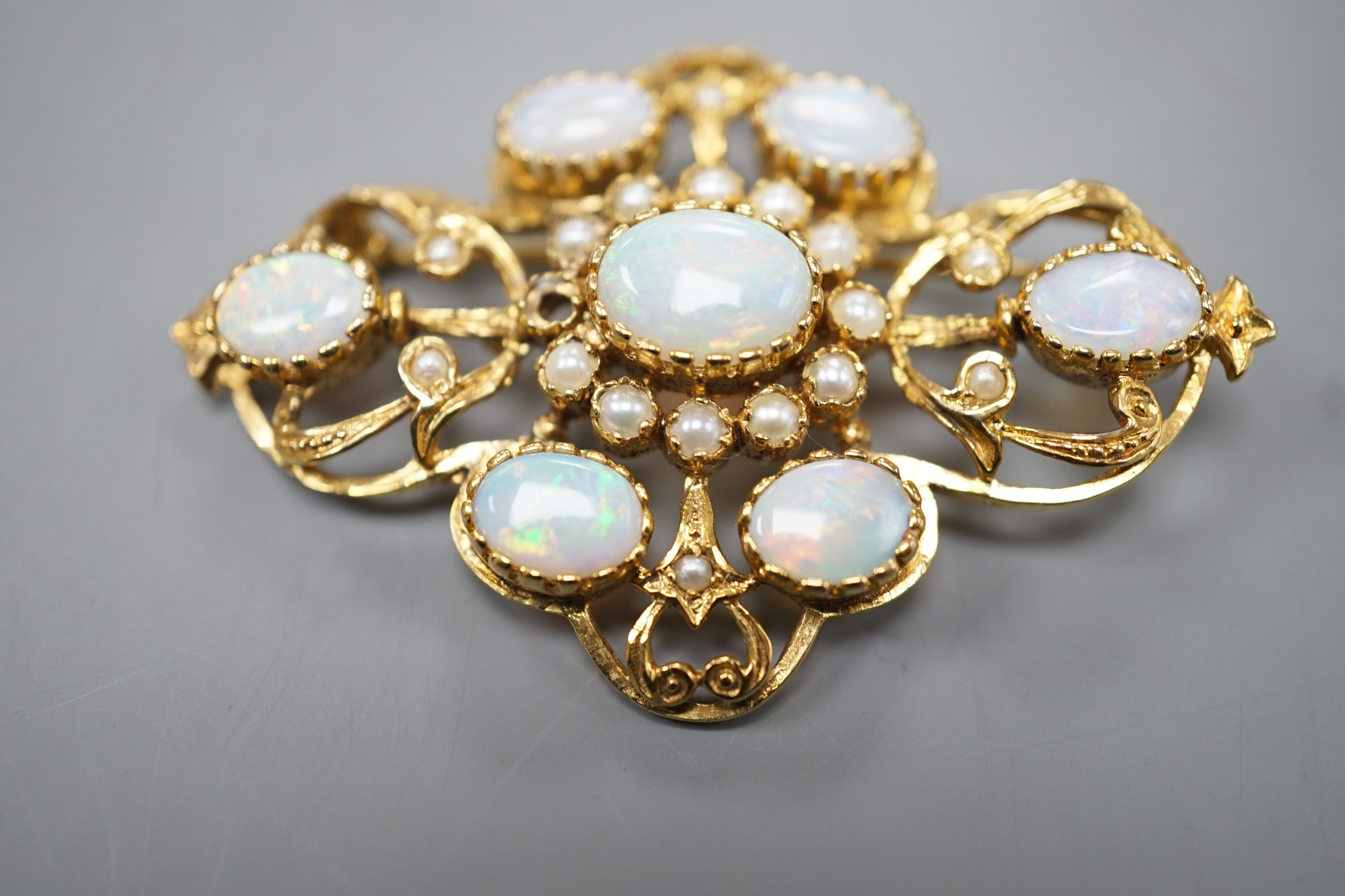 An early 1970's 9ct gold, graduated oval white opal and split pearl set brooch, of quatrefoil shape (pearl missing), 48mm, gross weight 9.3 grams.